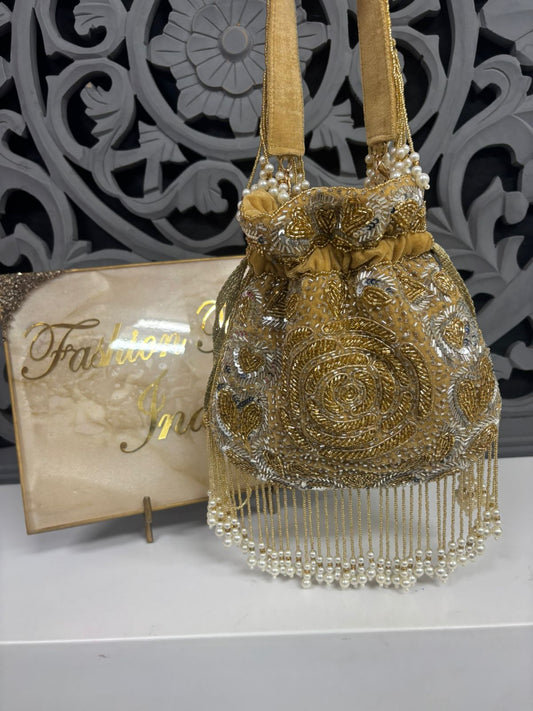 Gold beaded handbag with decorative patterns on a gray surface, with a decorative background.