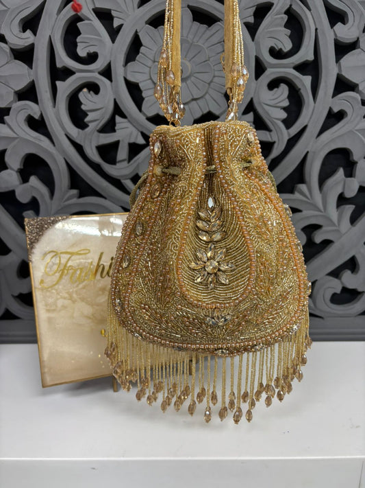 Gold beaded handbag with intricate design on a decorative background