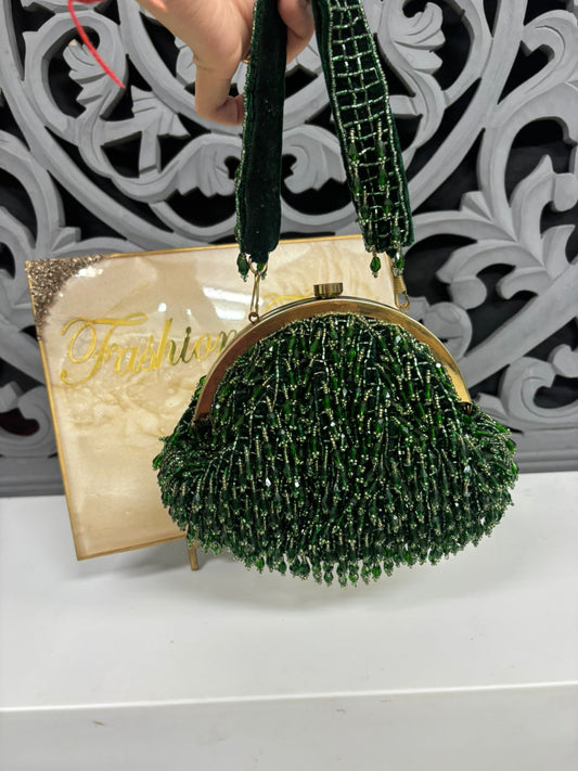 Green beaded handbag with gold frame and handle, displayed against a decorative white and gray background.