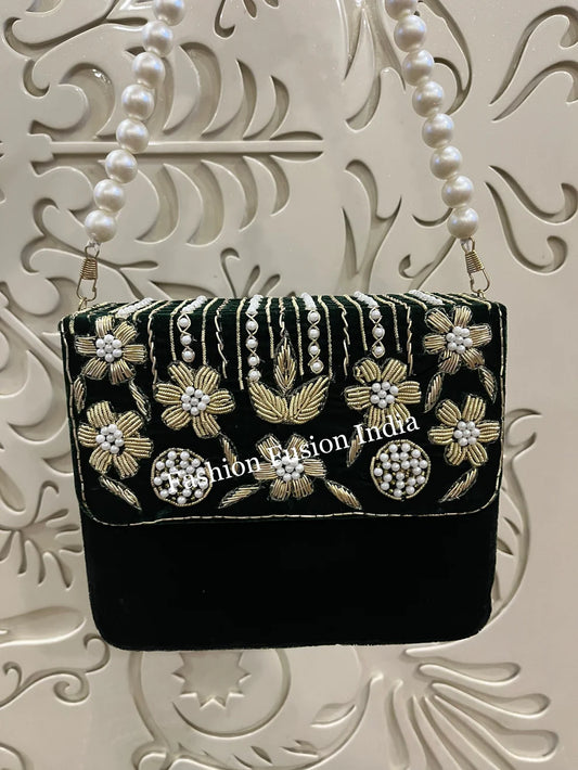 Green handbag with floral and pearl designs on a decorative white background