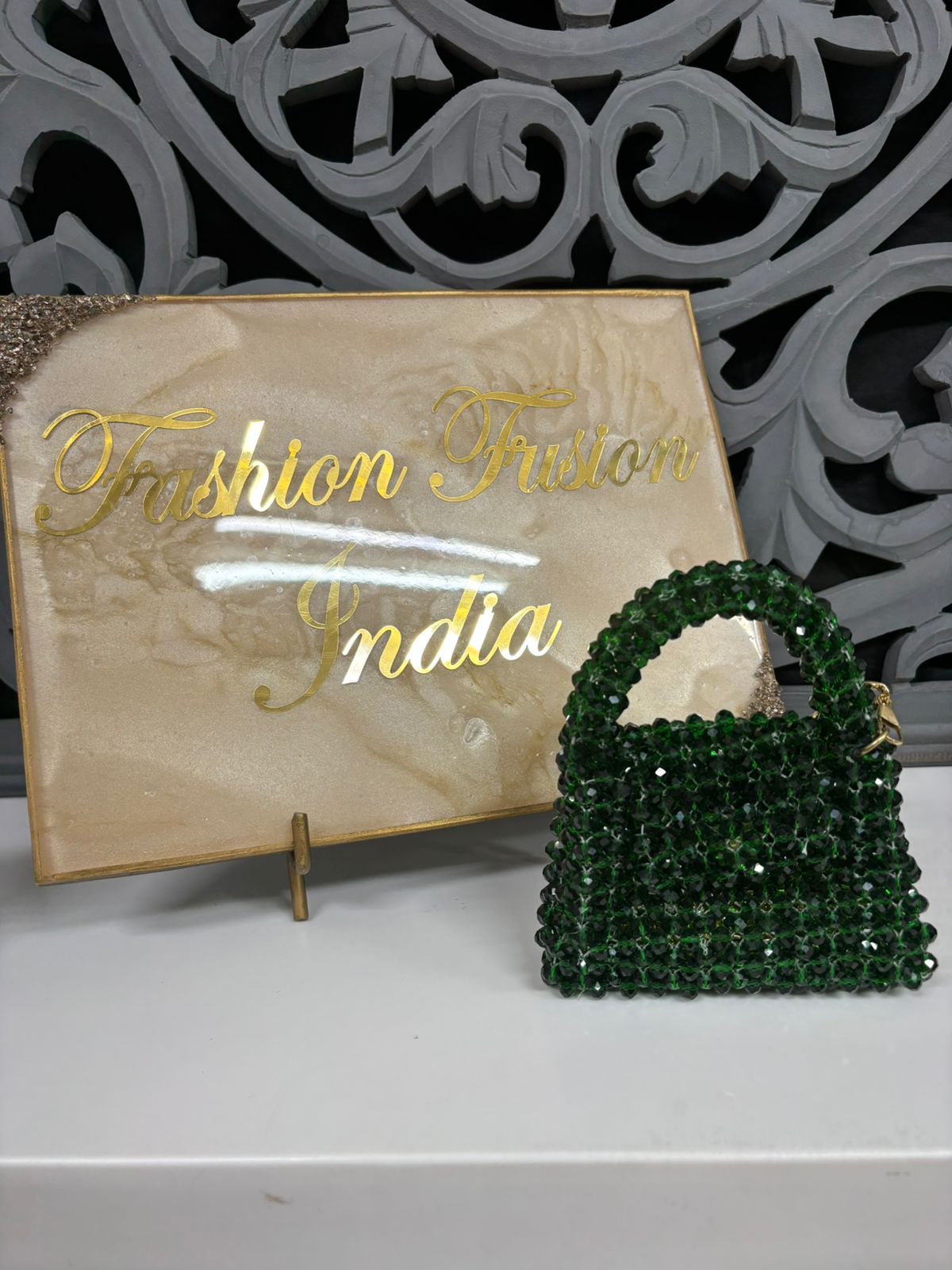 Green beaded handbag in front of a 'Fashion Fusion India' sign.