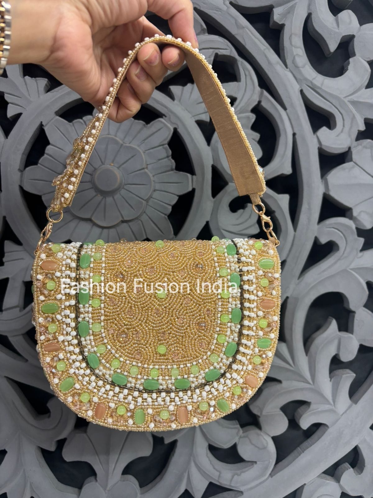 Decorative handbag with 'Fashion Fusion India' branding held by a hand against an ornate background.