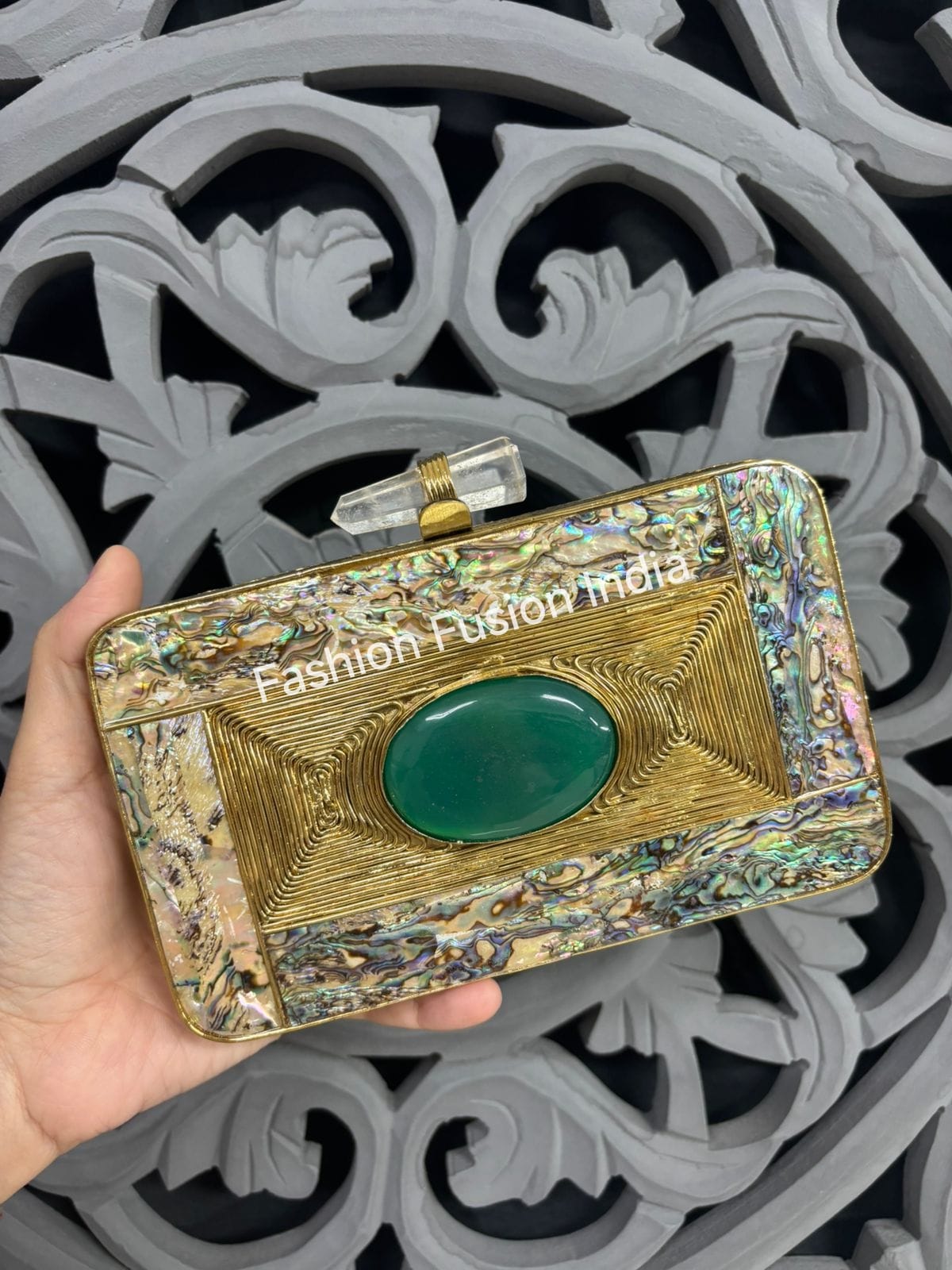 Decorative clutch held by a hand with intricate background
