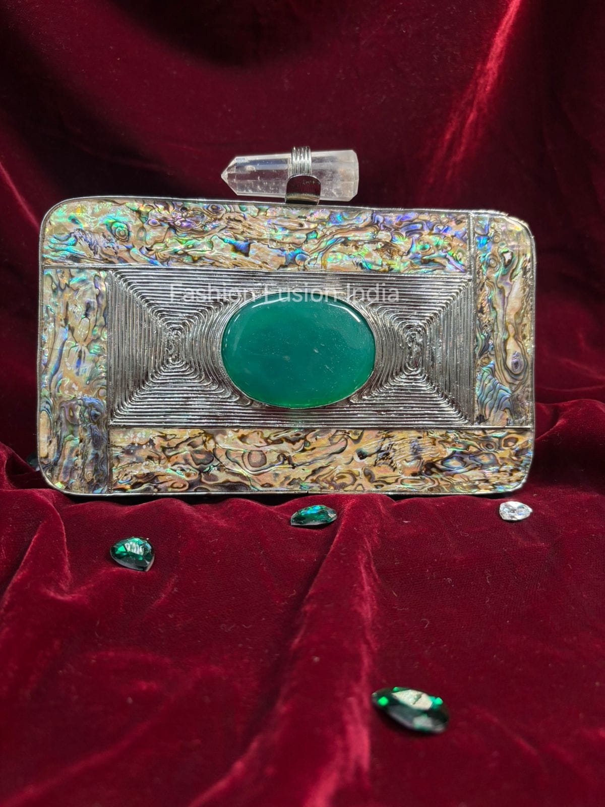 Decorative clutch with green gemstone on a red velvet background