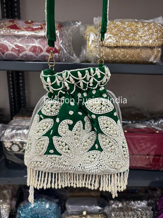 Green and white beaded handbag with fringes on a shelf with other bags.