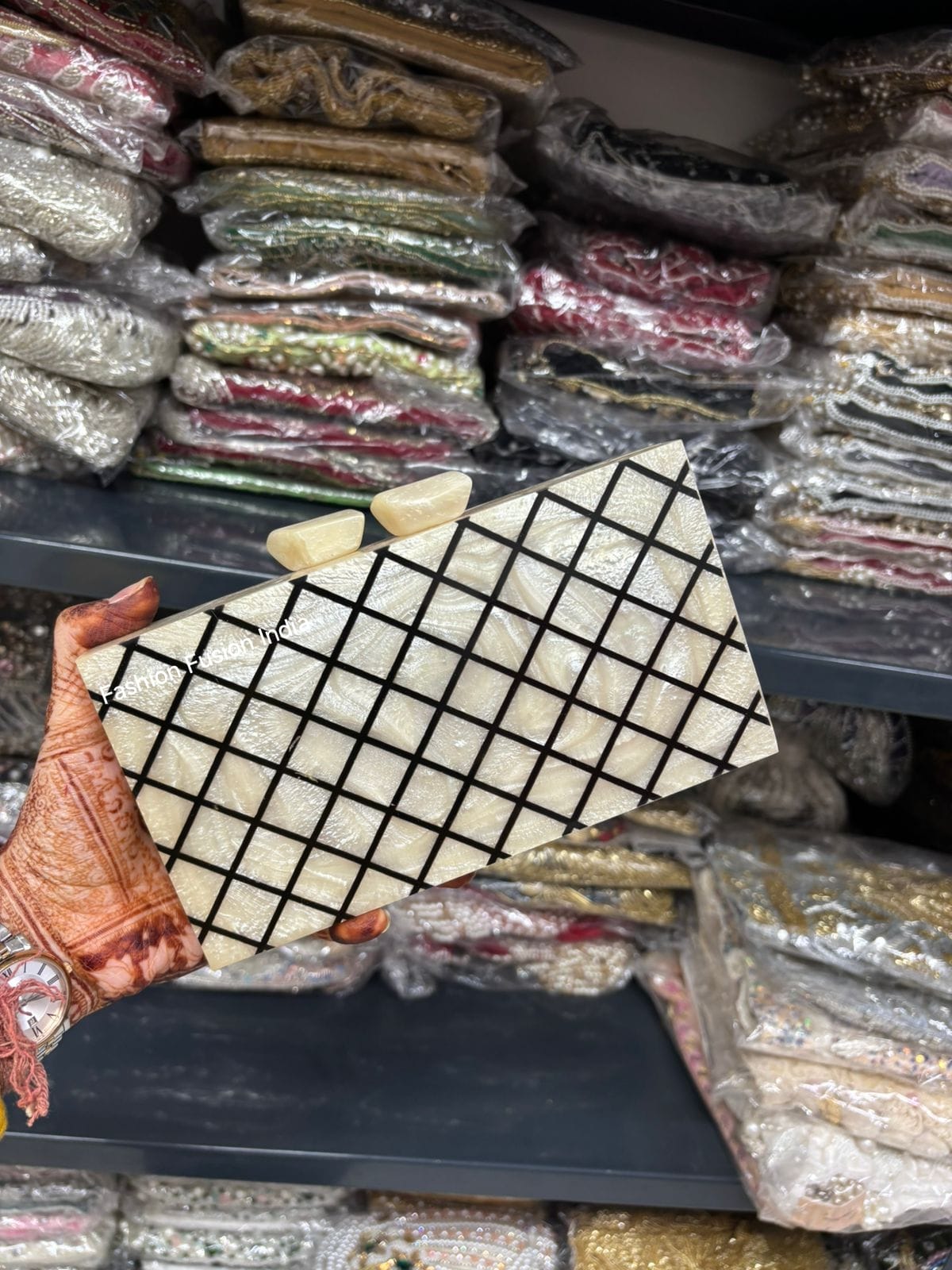 Grid-patterned stone held by a hand with a background of wrapped products.