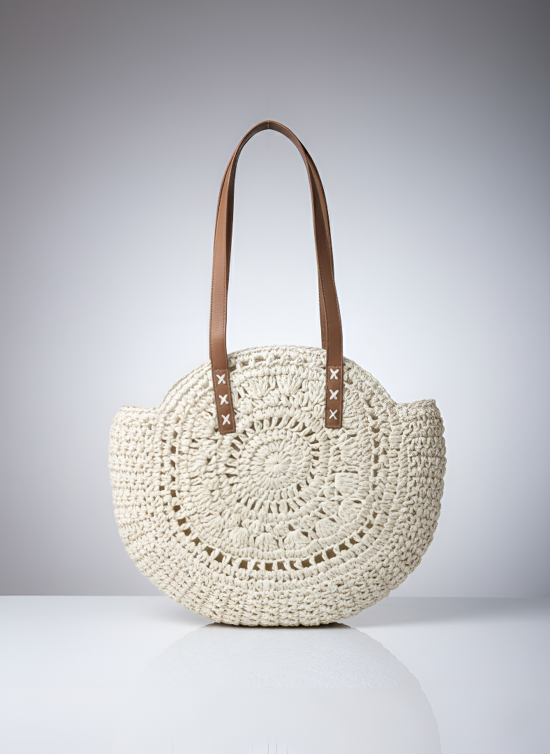 Round woven bag with brown leather handles on a gray background