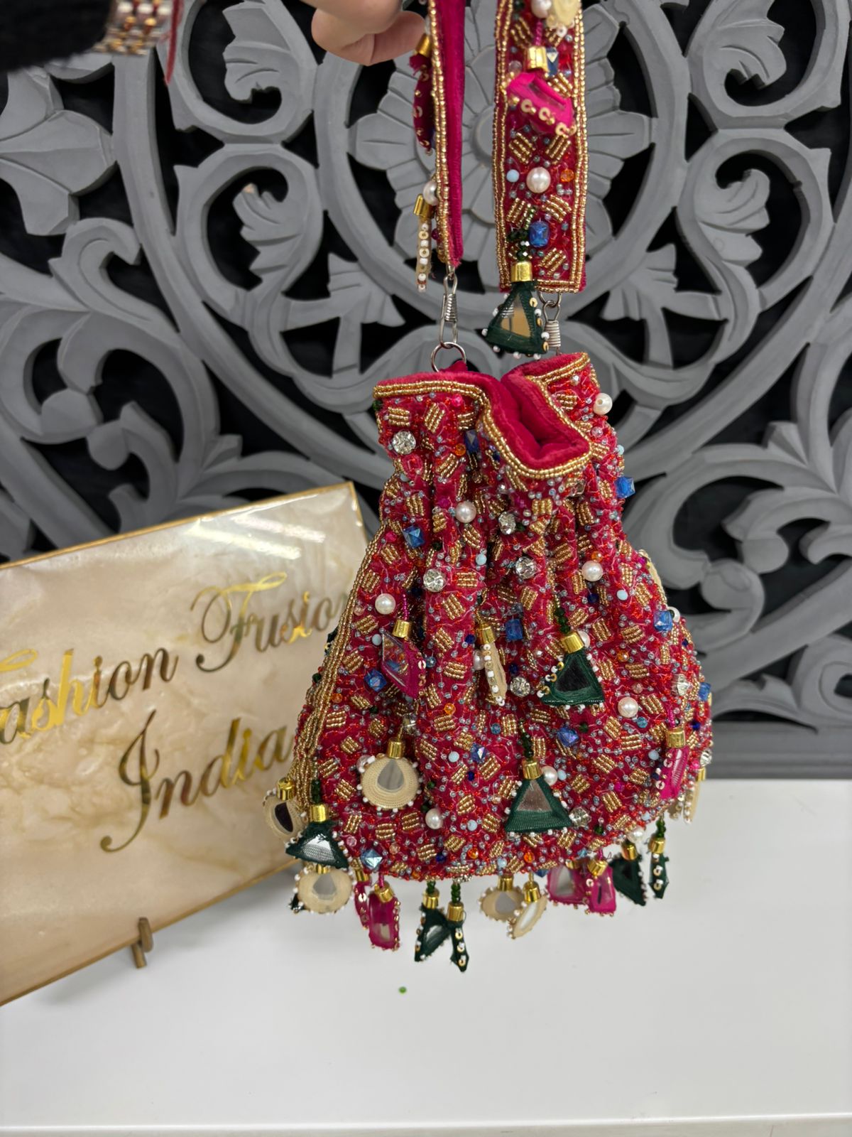 Decorative Hot Pink bag with gold and multicolor embellishments on a white surface.