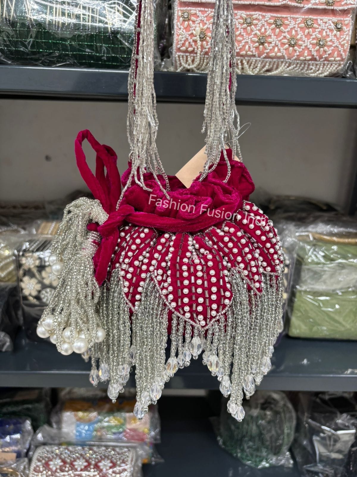 Hot Pink bag with white polka dots and fringes on a shelf with other items.
