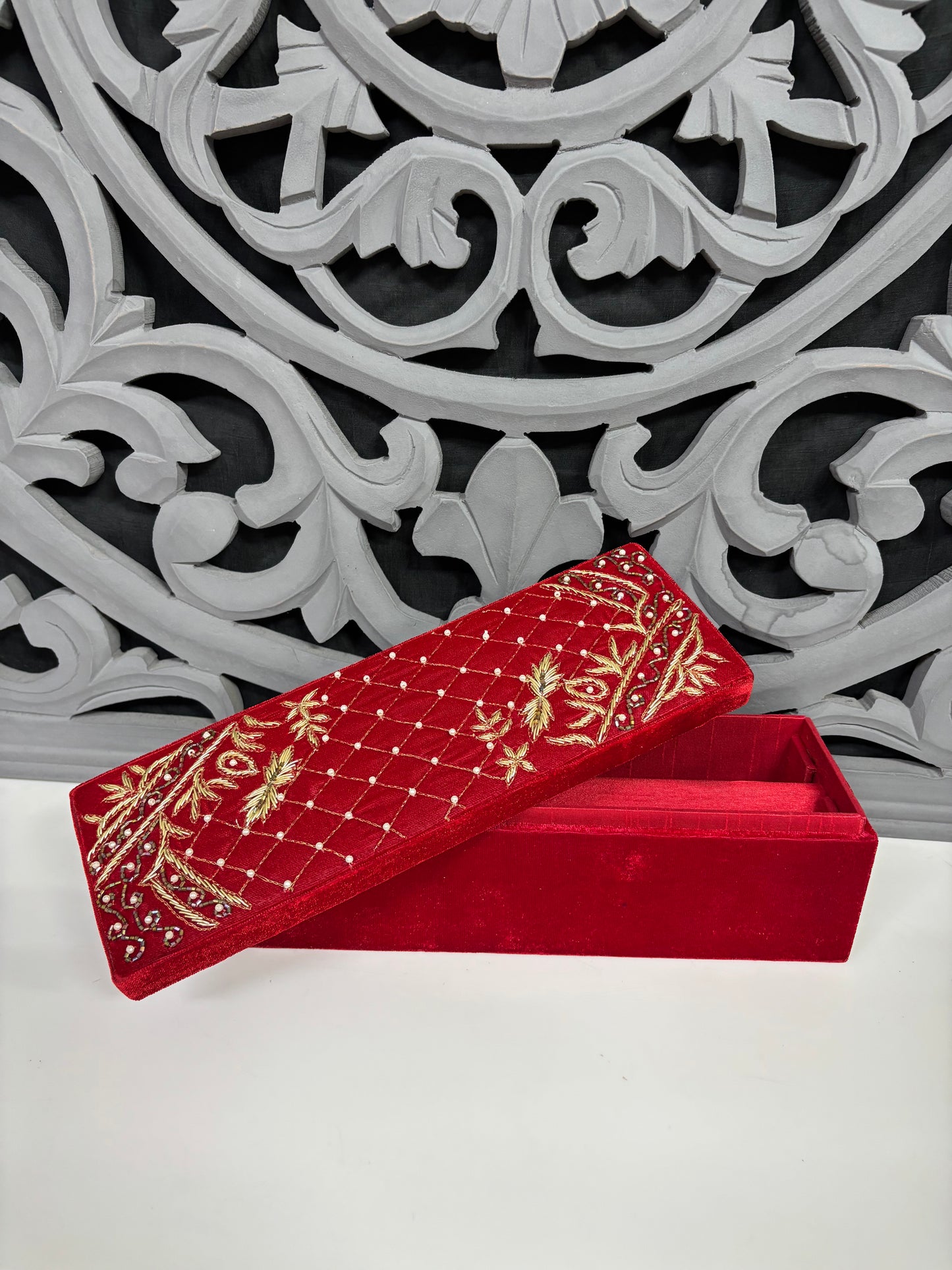 Red embroidered box with gold patterns on a decorative white and gray background