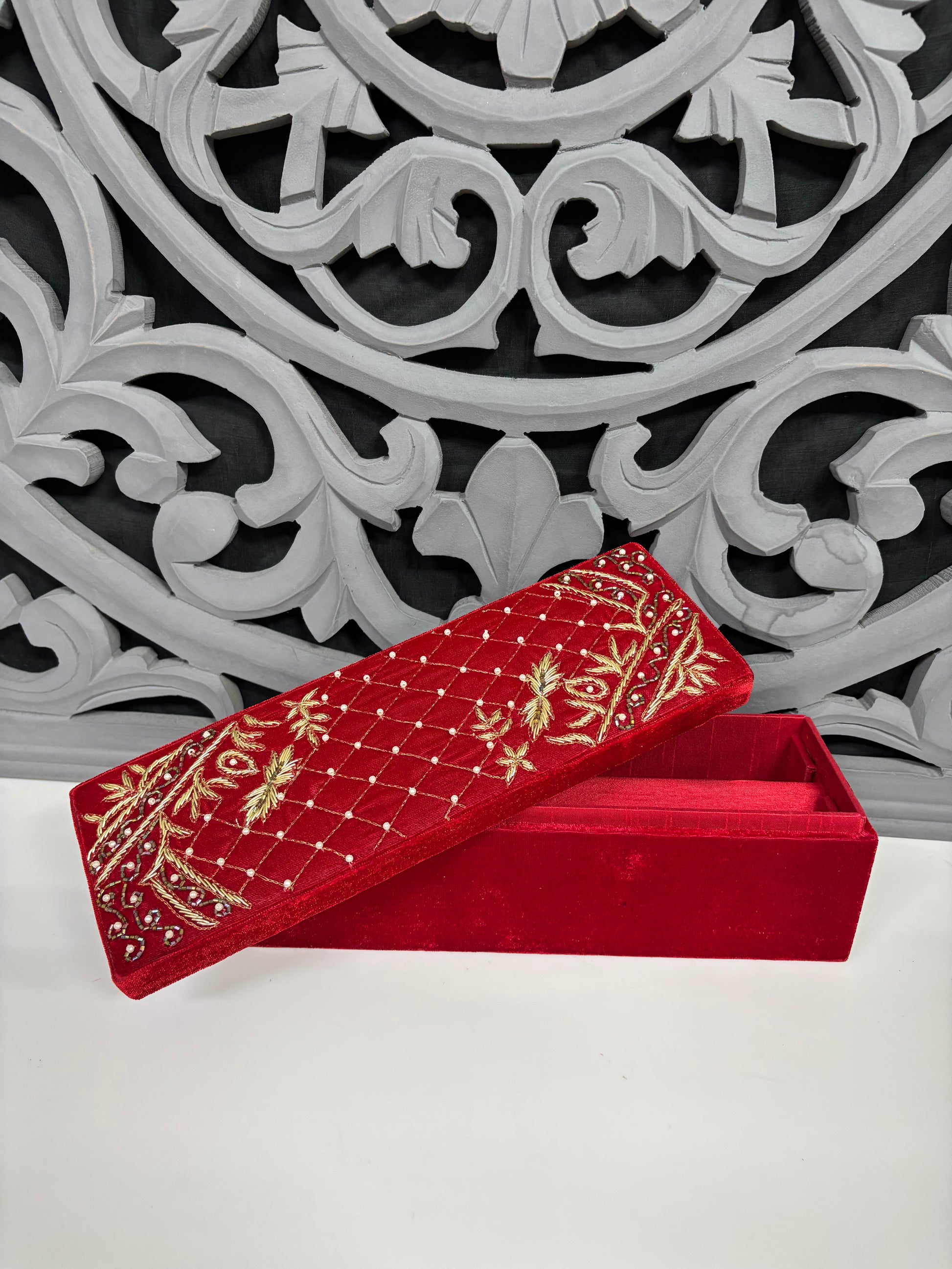 Red embroidered box with gold patterns on a decorative white and gray background