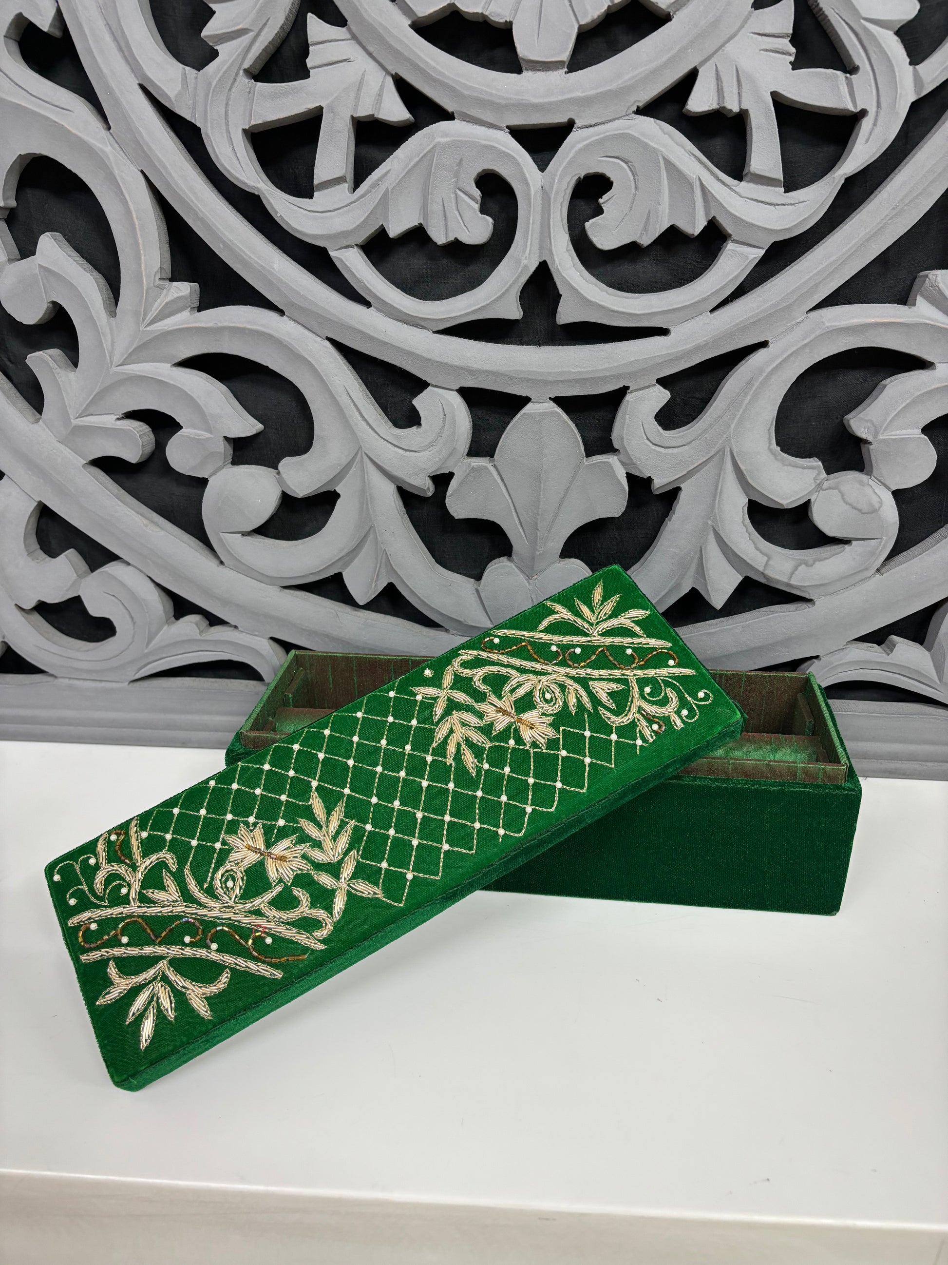 Green jewelry box with gold patterns on a decorative background