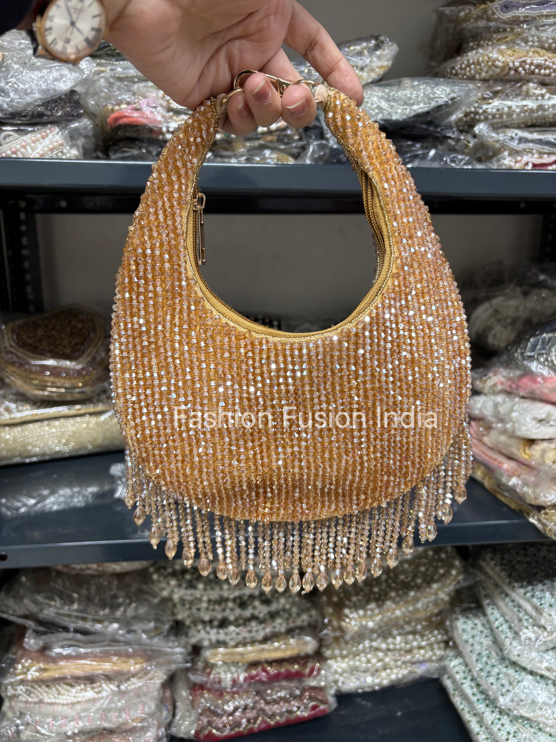 Gold beaded handbag held by a hand with a blurred background of similar bags.