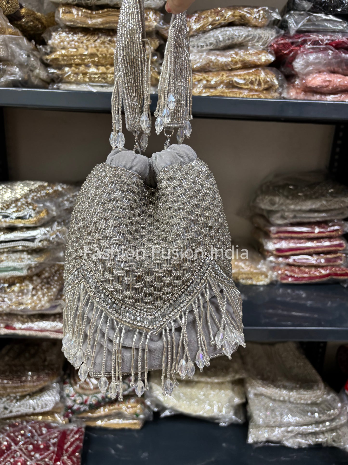 Decorative handbag with beaded details held above a display of similar bags.