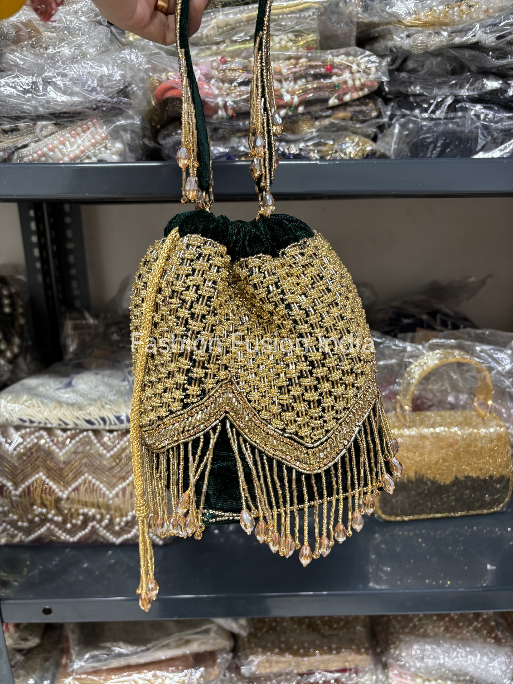 Gold and green handbag with fringe details on a shelf.
