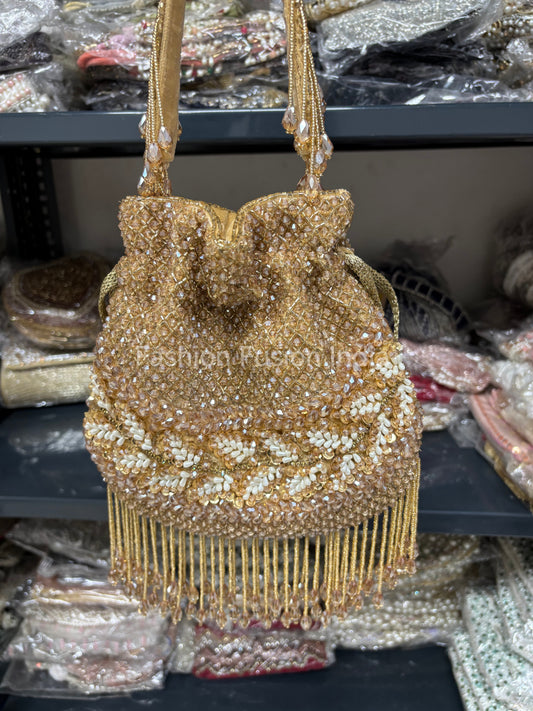 Gold beaded handbag with fringe on a blurred background