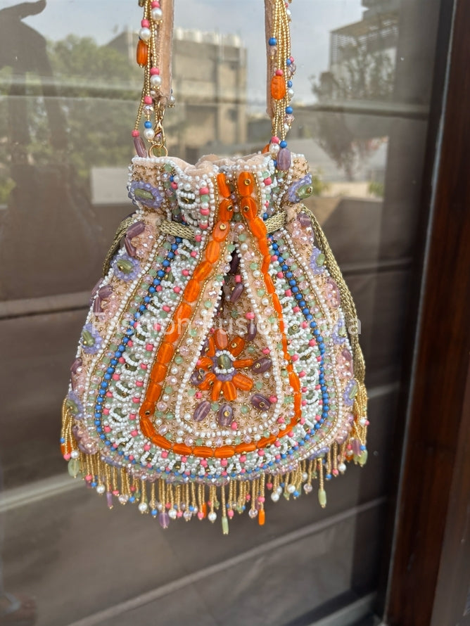 Decorative handbag with beads and embroidery hanging on a glass door.