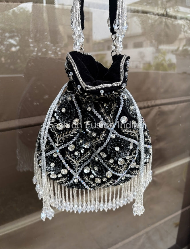 Black handbag with silver beading and fringes on a reflective surface