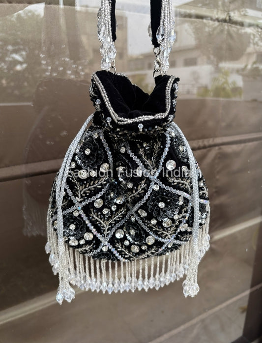 Black handbag with silver beading and fringes on a reflective surface