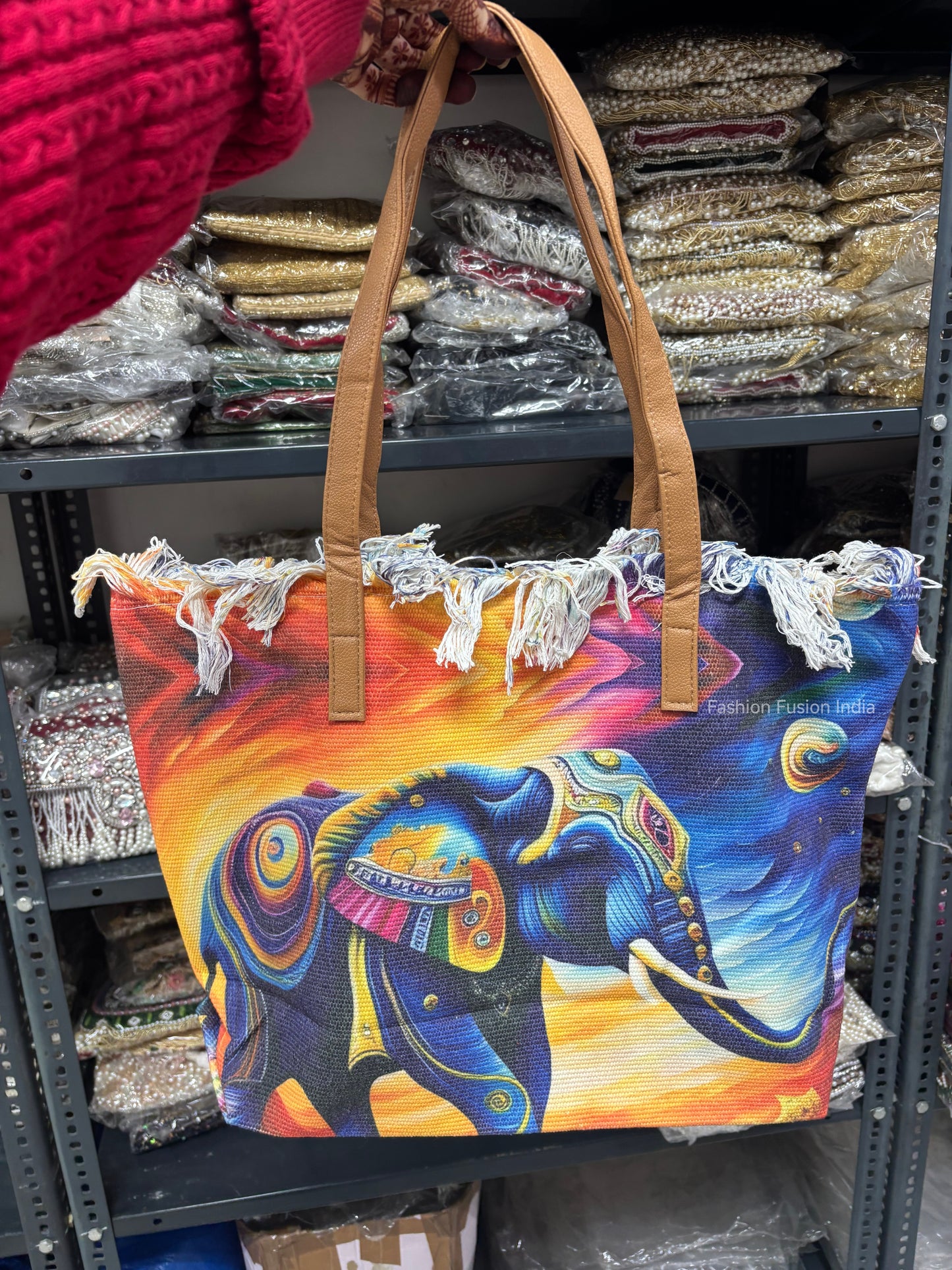 Colorful tote bag with an elephant design held by a person in a store setting.