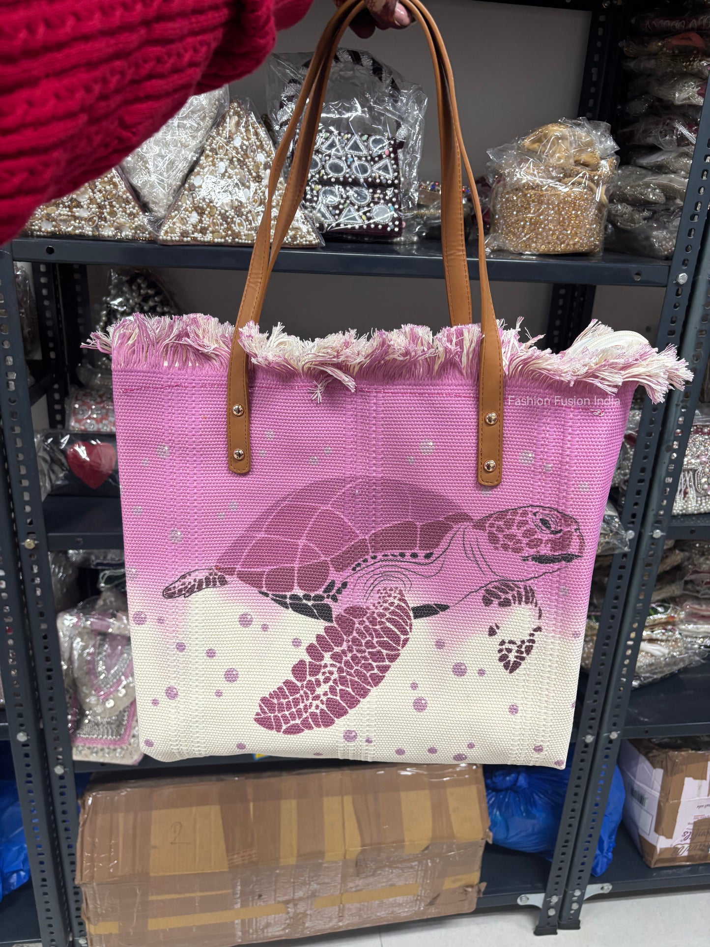 Pink tote bag with turtle design held by a person in a store setting