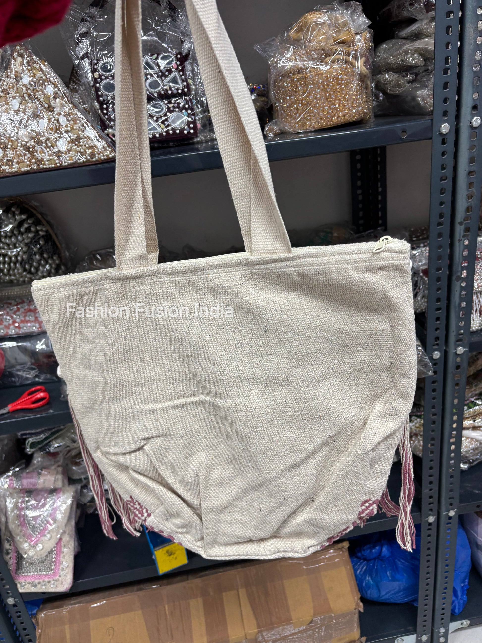 Beige tote bag with fringe details on a store shelf, labeled 'Fashion Fusion India'.