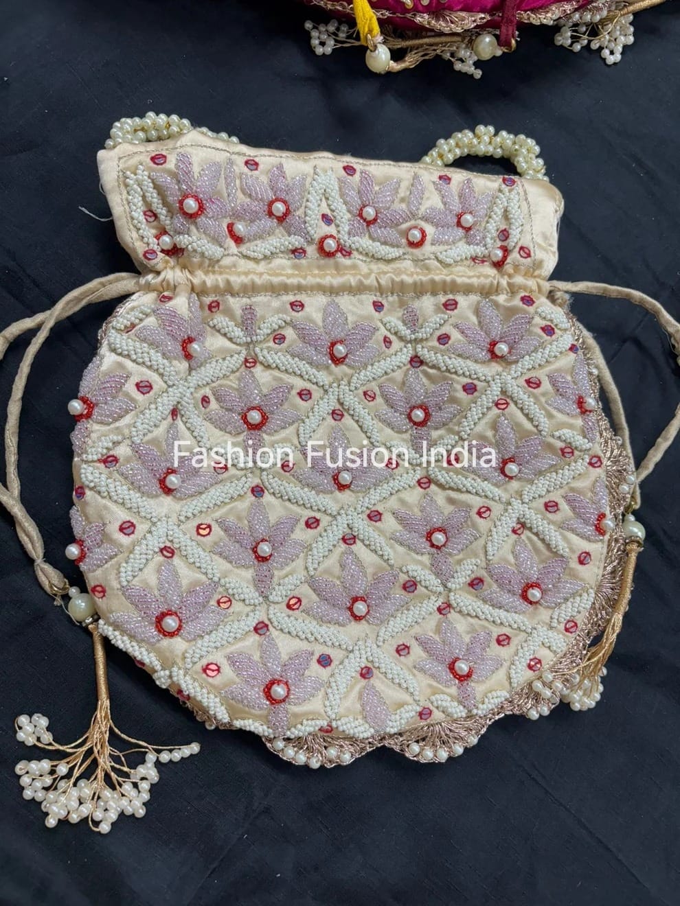 Decorative handbag with floral patterns and red embellishments on a dark background, branded 'Fashion Fusion India'.