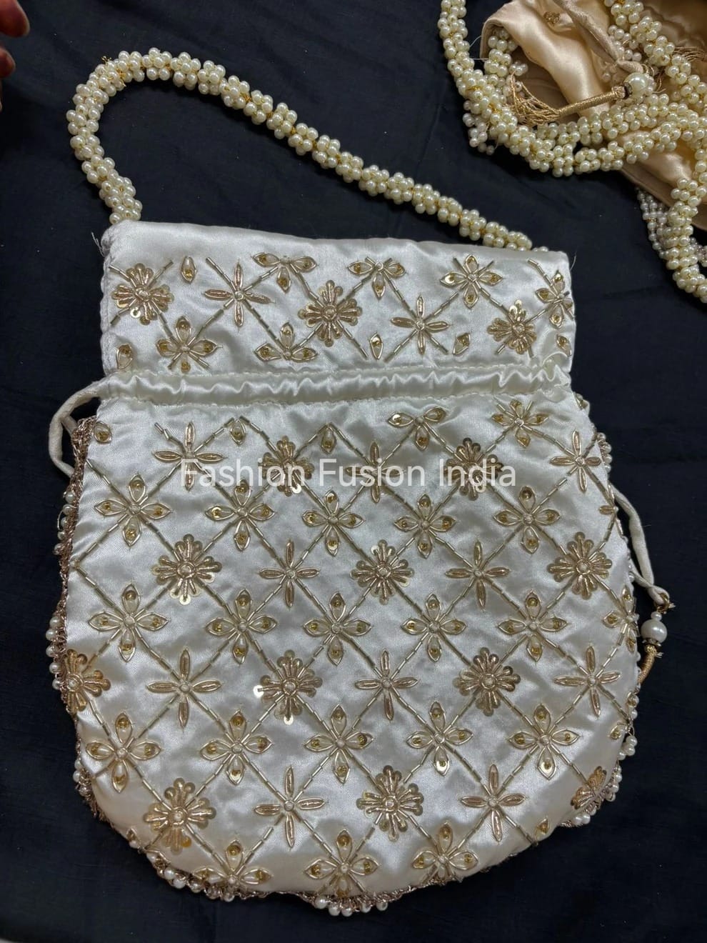 White handbag with gold embroidery and a pearl handle on a dark background, branded 'Fashion Fusion India'.