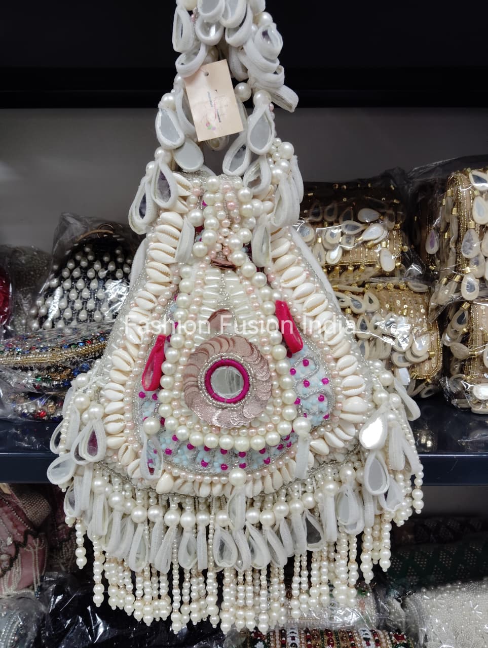 Decorative bag with pearls and beads, hanging against a blurred background.