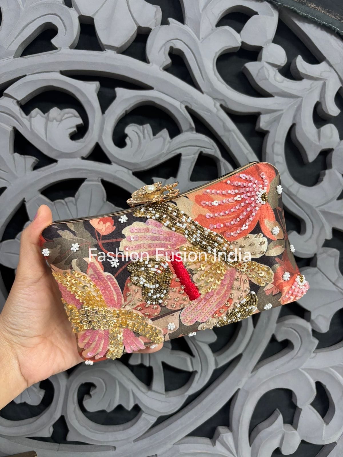 Decorative phone case with floral patterns and embellishments, held against an ornate gray background.
