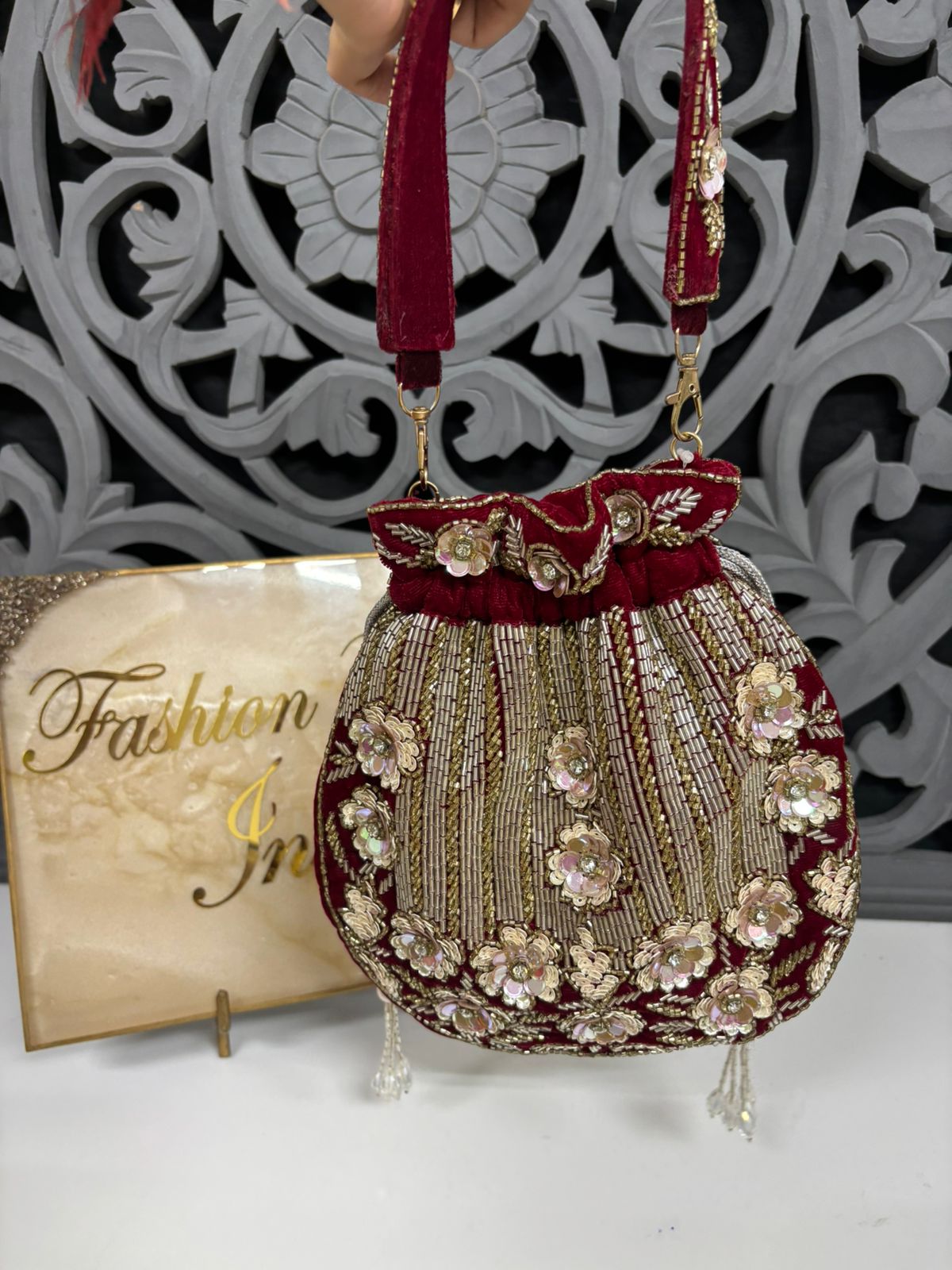 Decorative handbag with floral patterns and red accents on a white surface.