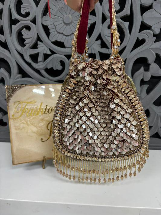 Decorative handbag with sequins and fringes on a white surface with a decorative background.