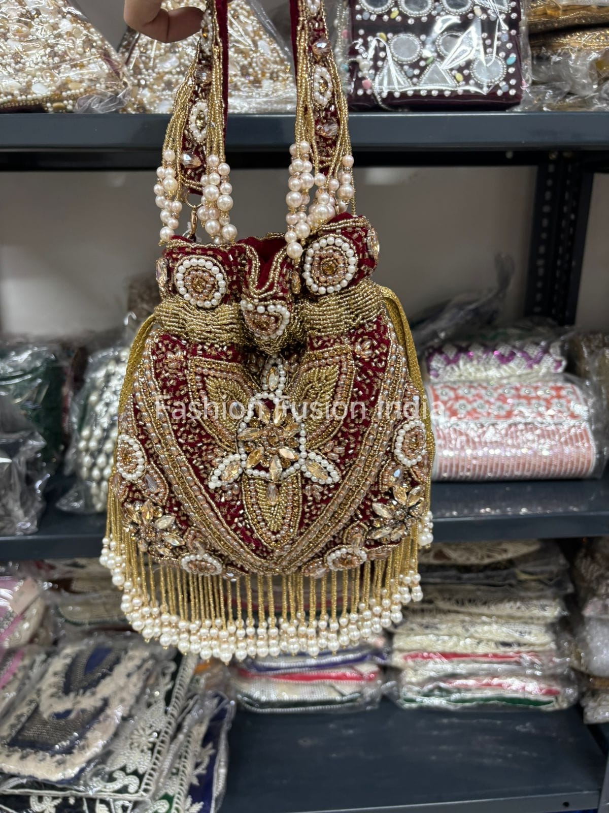Decorative handbag with pearls and gold embroidery on a shelf with similar bags.