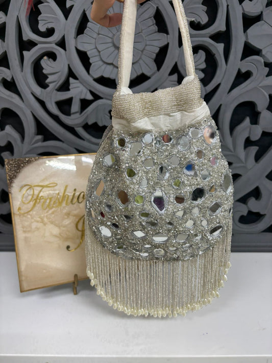 Decorative handbag with beads and fringes on a white surface with a decorative background.