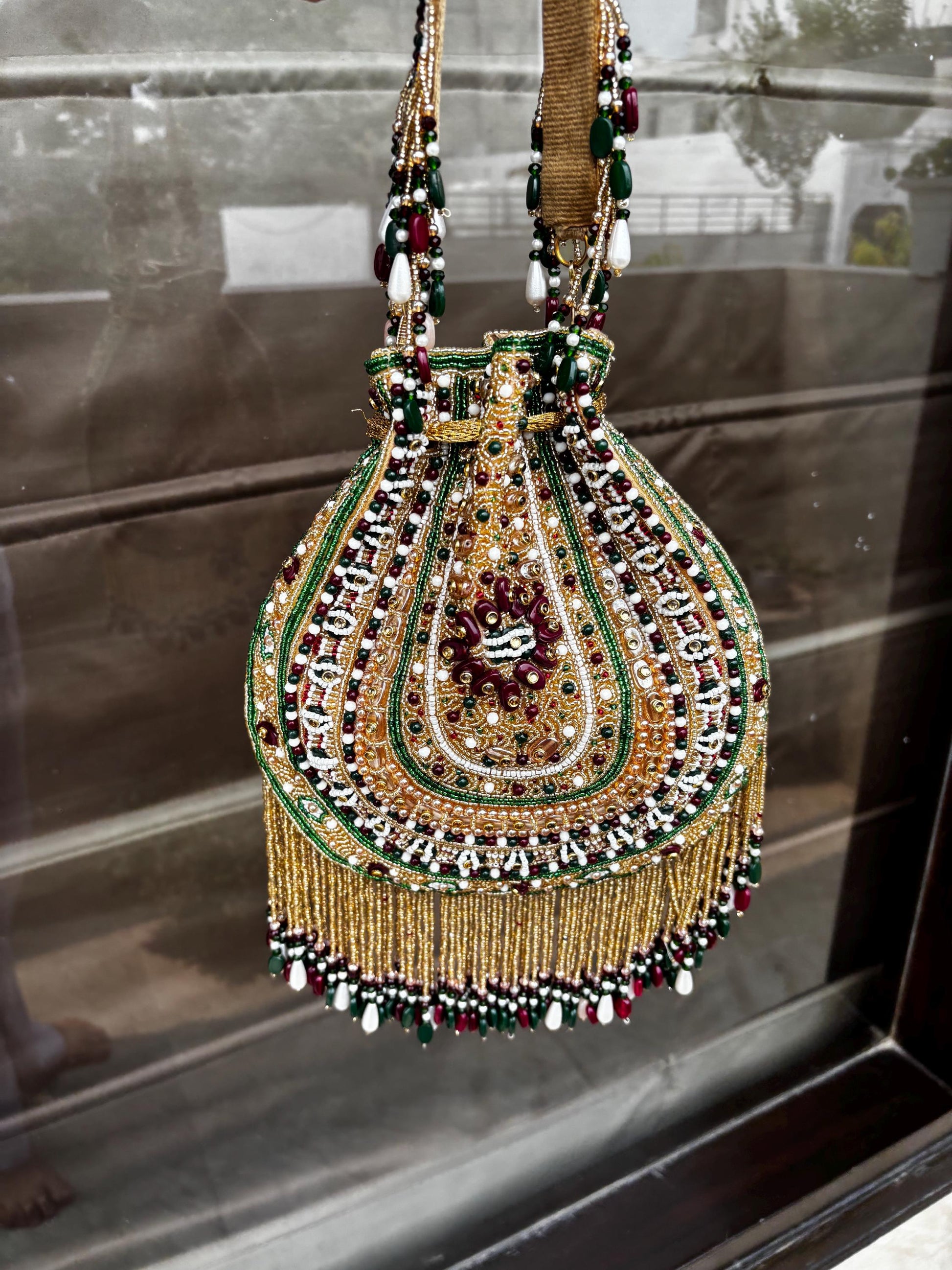 Decorative handbag with intricate beadwork and embroidery on a reflective surface