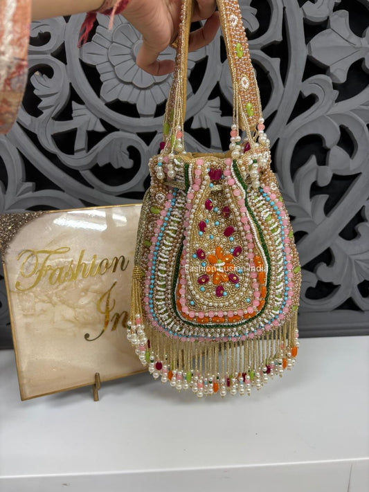 Decorative handbag with beads and stones held by a person, with a 'Fashion' magazine in the background.