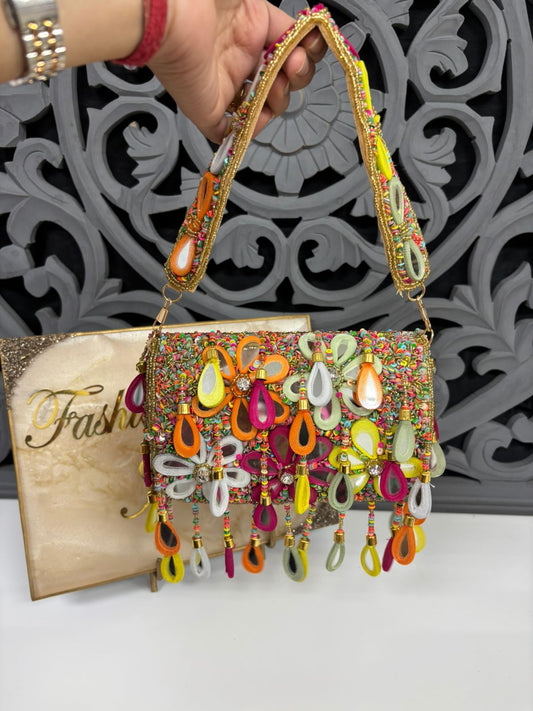 Decorative handbag with colorful beads and a gold handle against a decorative wall.