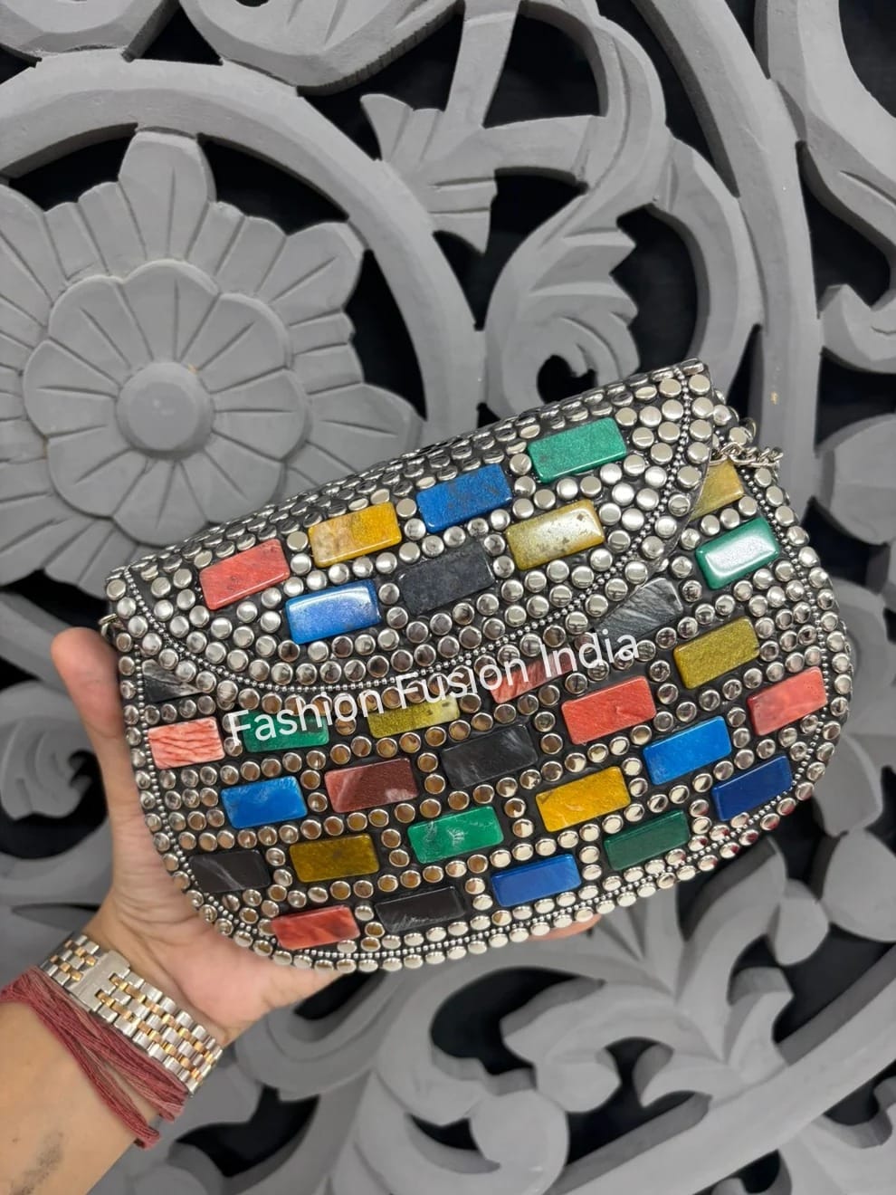 Colorful handbag with 'Fashion Fusion India' branding held by a hand against a decorative background.