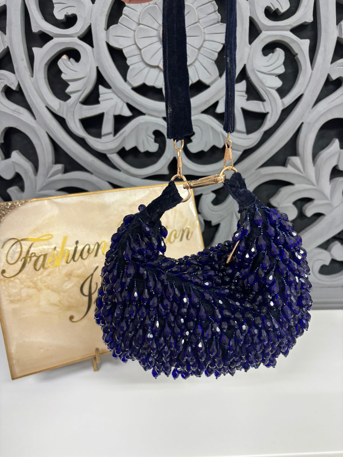 Navy blue beaded handbag with gold clasp on a decorative background
