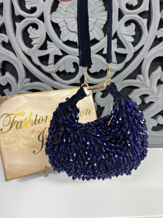Navy blue beaded handbag with gold clasp on a decorative background
