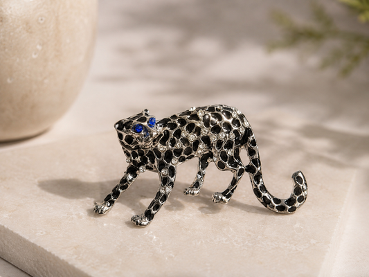 Silver leopard brooch with black and blue gemstones on a light surface