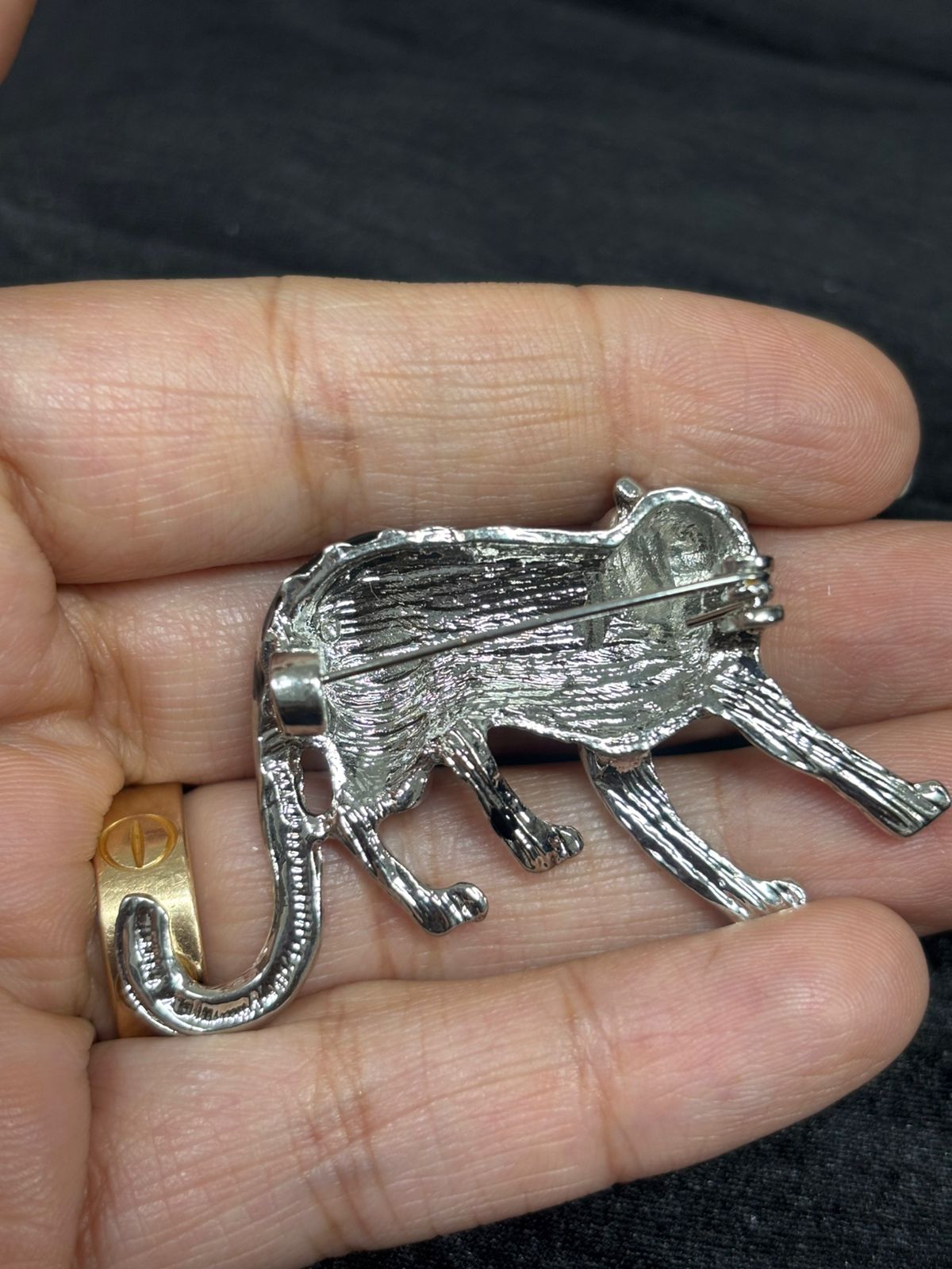 Silver panther pendant held in a hand with a blurred background