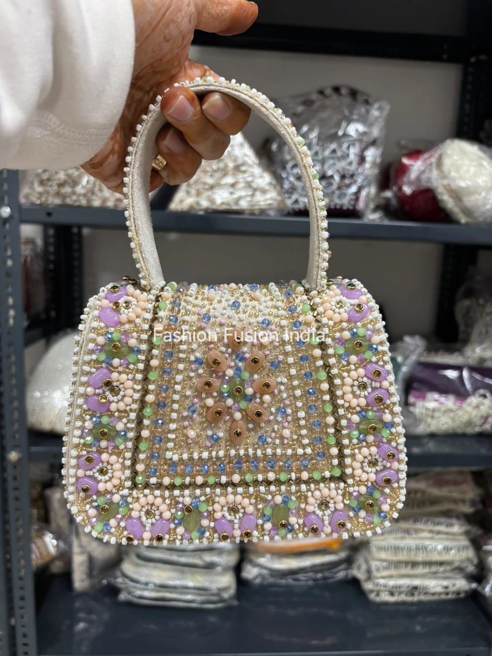 Handbag with colorful beadwork held by a person, with 'Fashion Fusions India' branding.