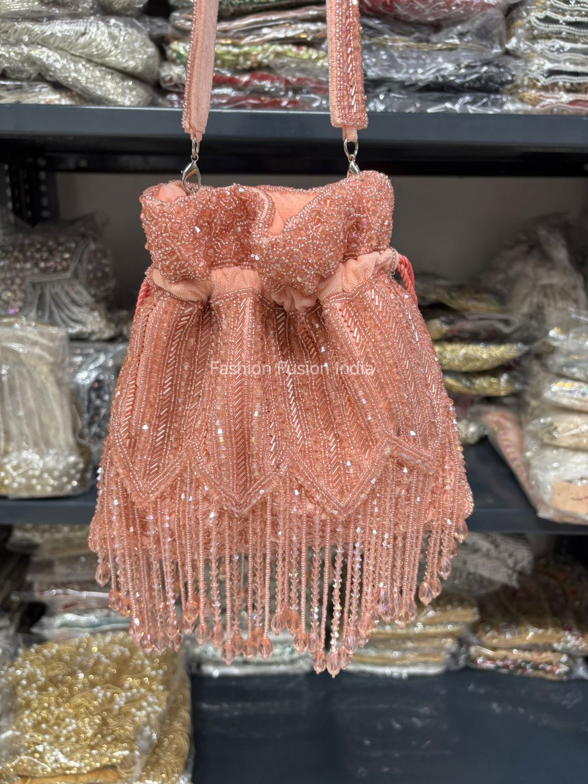 Rose gold beaded handbag with fringe details on a blurred background of similar bags.
