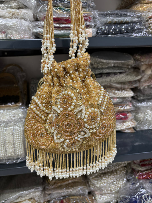 Gold beaded handbag with pearls on a shelf with similar bags in the background