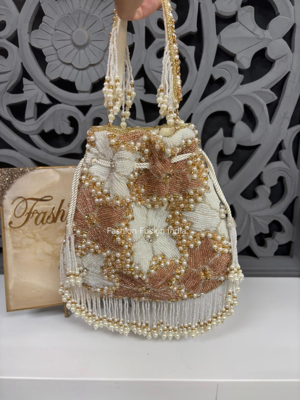 Beaded handbag with floral pattern on a white surface, with 'Fashion' magazine in the background.