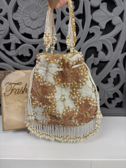 Beaded handbag with floral pattern on a white surface, with 'Fashion' magazine in the background.