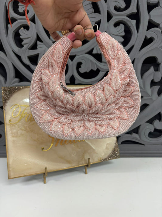 Pink textured handbag held by a hand against a decorative gray background