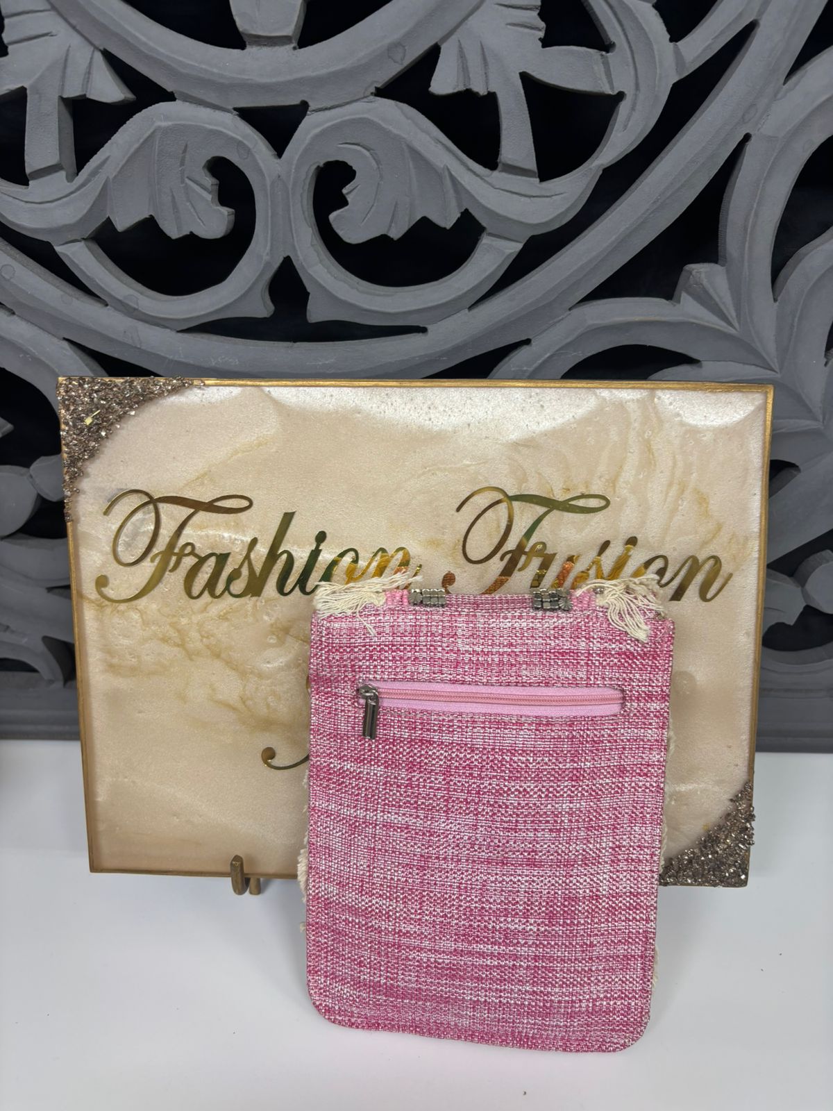 Pink textured pouch with decorative elements on a gold card with 'Fashion Fusion' text.