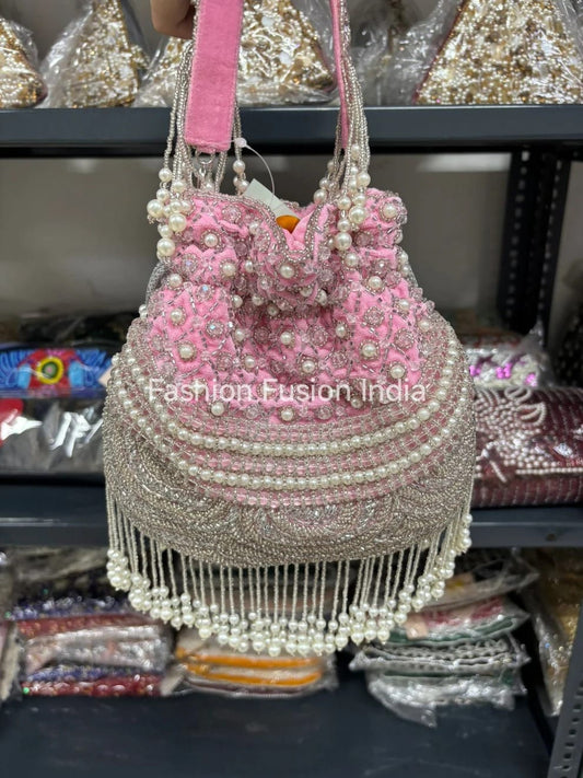 Pink handbag with pearl embellishments on a blurred background